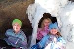 The girls found a cool ice cave and couldn't wait to get inside of it.